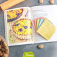 Essuie-tout lavables colorés posés sur un livre de recettes, parfaits pour une cuisine écologique et pratique.