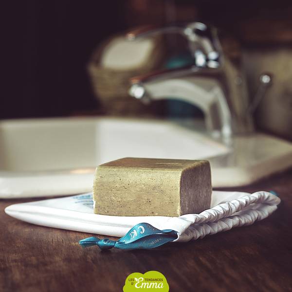 Savon détachant solide posé sur un support près d'un lavabo, parfait pour détacher naturellement les vêtements.